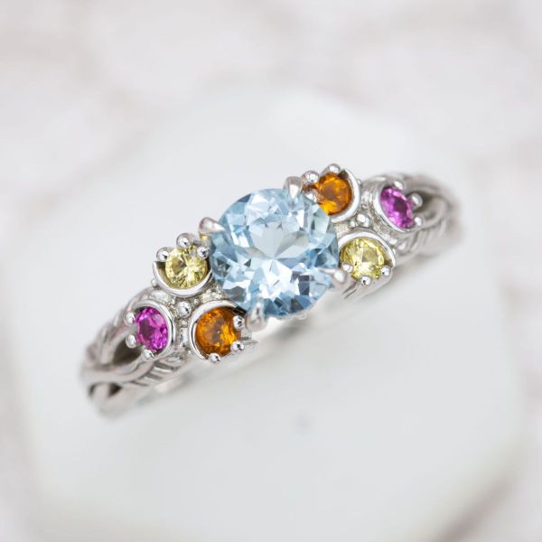 This Zelda inspired engagement ring features an aquamarine center stone and accent gems shaped like Zora’s Sapphire.