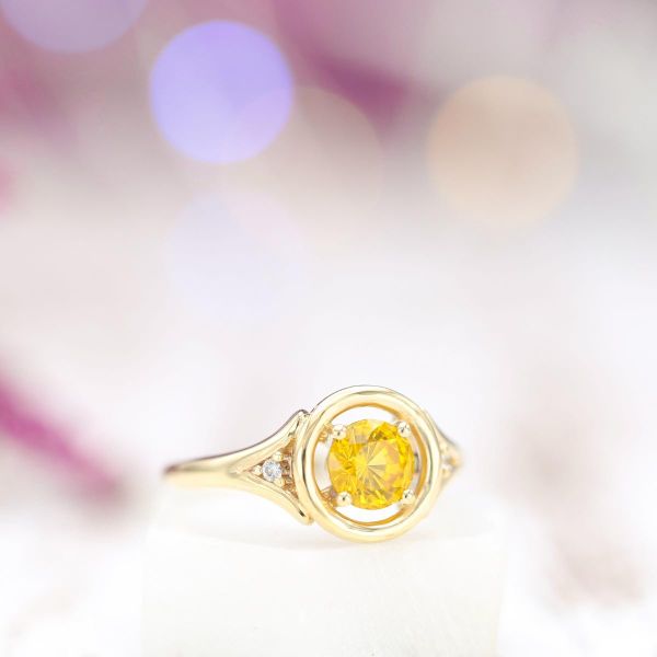 这枚订婚戒指的黄色蓝宝石镶嵌在金色光环上，镶有钻石。