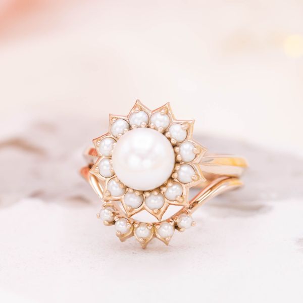 这款完美甜美的花戒指使用珍珠籽来突出柔软弯曲的花瓣。