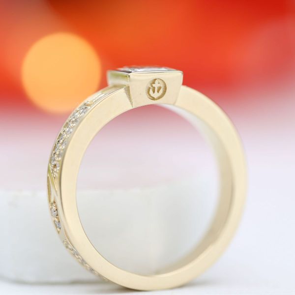 A sunny yellow gold band with a bezel-set diamond center stone creates a masculine look in this men’s engagement ring.