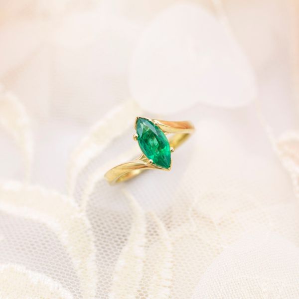 The marquise emerald in this bypass engagement ring setting is a natural emerald.