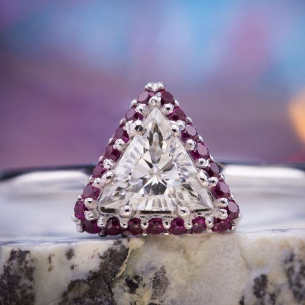 A more unusual choice for the center stone: a triangle cut with a ruby halo repeating its shape.