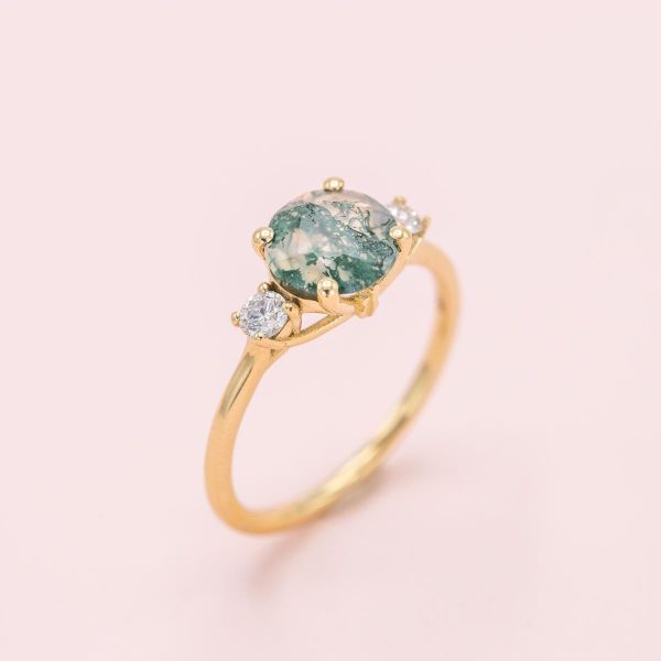 In this yellow gold ring, both sides of the moss agate center stone sport a diamond.