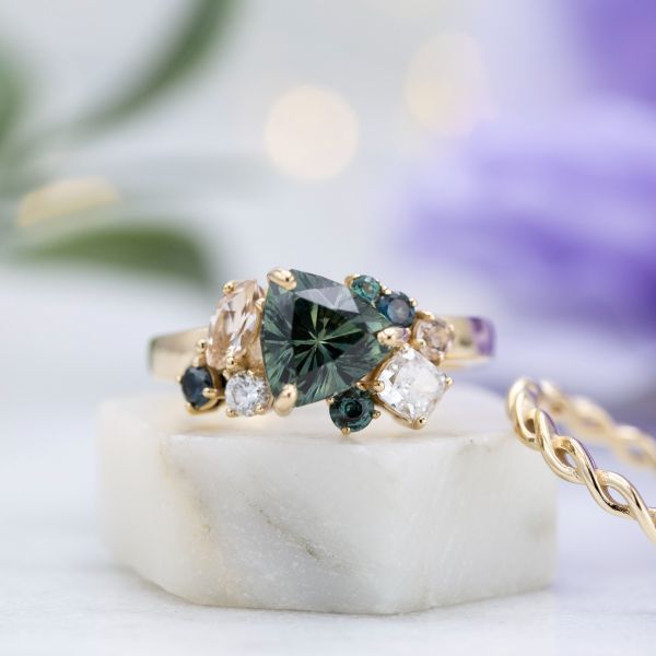 一枚令人难以置信的绿色蓝宝石万亿切割锚混合宝石在这一簇订婚戒指。