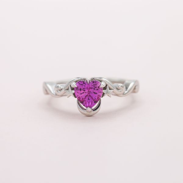 A heart-shaped pink sapphire is embraced by the moon and stars.