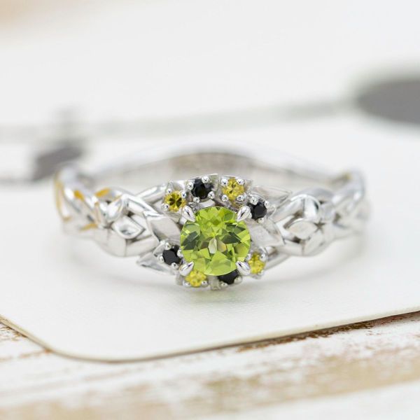 Two fandoms combine in one engagement ring with a peridot center stone and black and yellow accent gems.