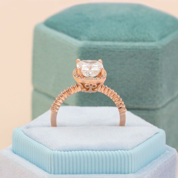 A diamond halo surrounds a cushion cut lab diamond on this rose gold engagement ring.