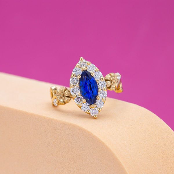 Bright blue lab sapphire engagement ring with a diamond halo and yellow gold band.