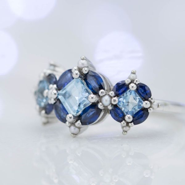 A stunning and unusual setting of marquise cut sapphires around princess cut aquamarine to create a faux-cushion layout.