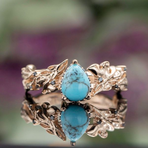 Wolf silhouettes are woven in the intricate rose gold band, surrounding the beautifully veined pear turquoise center stone.