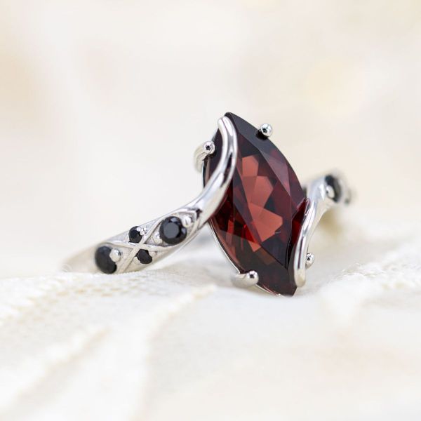 A marquise cut Mozambique garnet pairs with black spinel accents to create this powerful engagement ring.