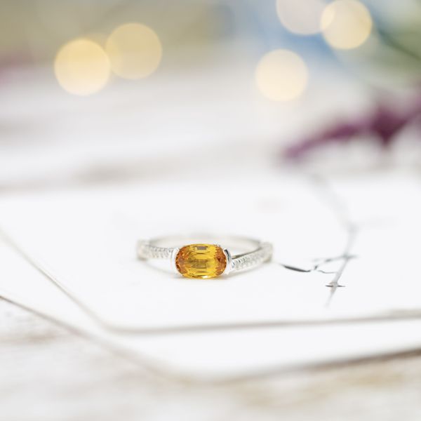 A sunny yellow sapphire sits in the center of this east-west engagement ring.