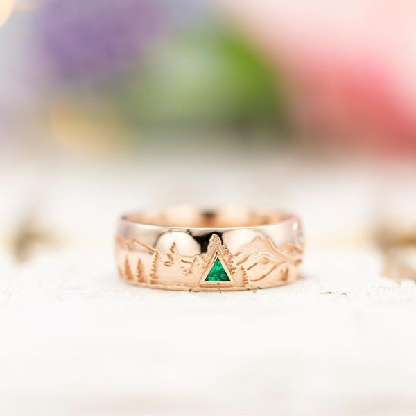The minimalistic mountains on this rose gold wedding band are accentuated by a triangle emerald tree.