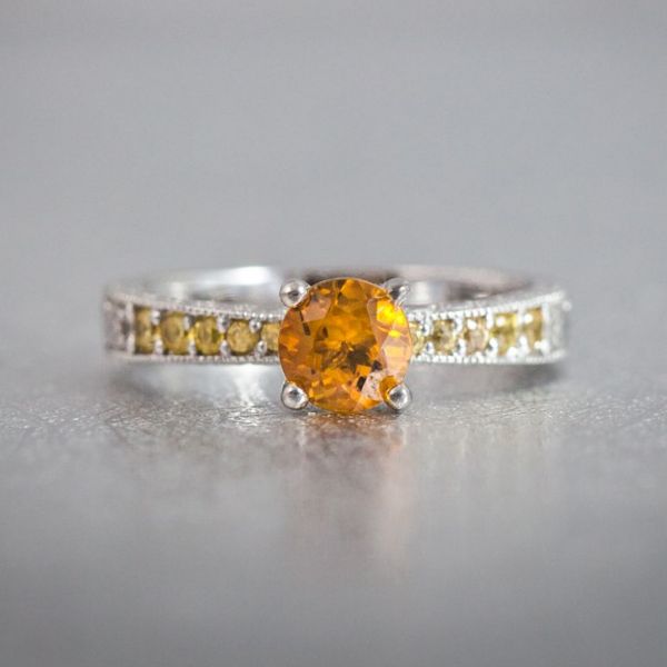 The cooler shade of yellow sapphires on the band helps bring out the rich orange tone of this ring's center citrine.