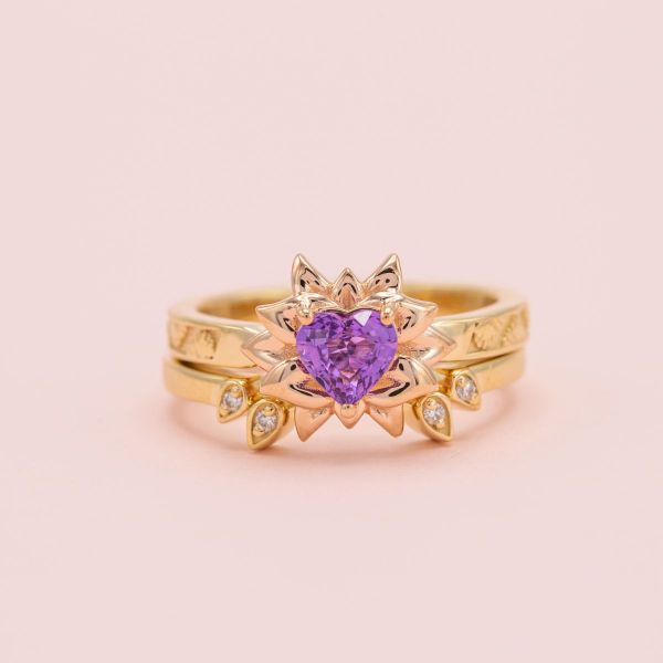 Heart shaped purple sapphire in yellow gold setting with floral details.