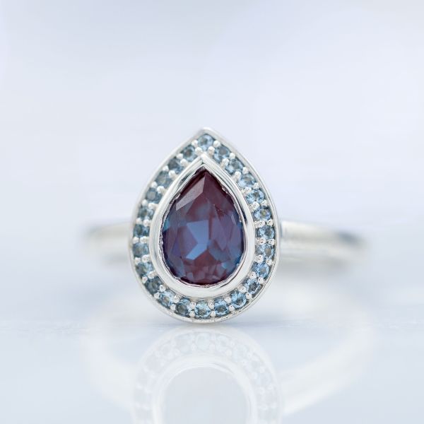 The light blues of this aquamarine halo draw out the blue shades of the alexandrite center stone.