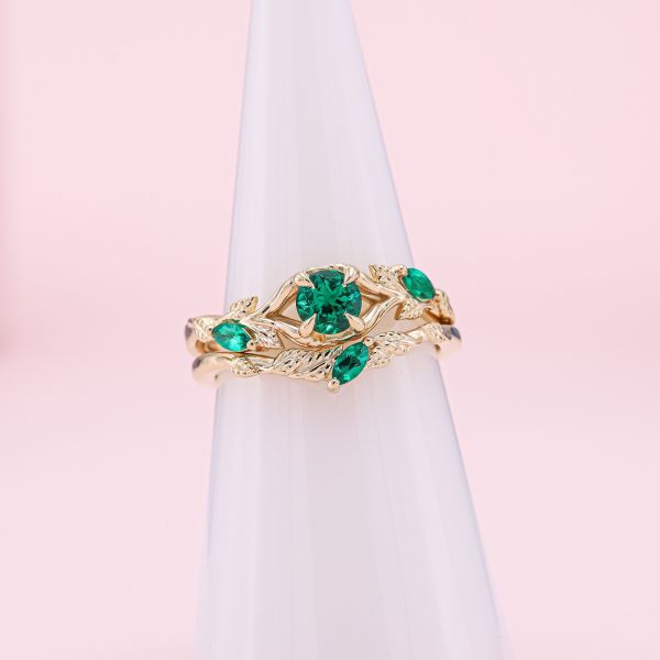 This nature inspired engagement ring holds a smattering of emeralds with a brilliant round taking center stage.