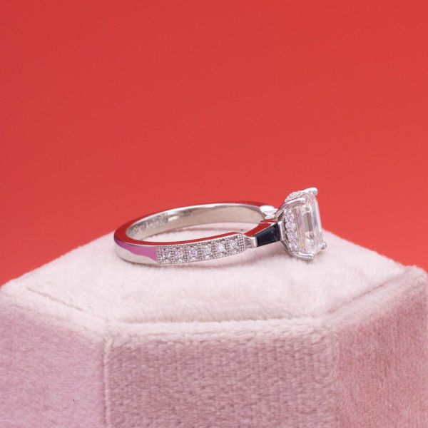 A hidden halo sits just under the emerald cut moissanite center stone in this family inspired engagement ring.