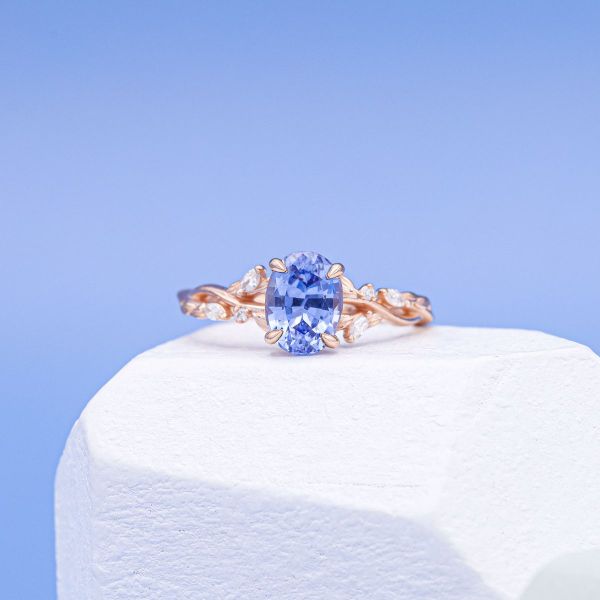 A natural blue, oval cut sapphire in rose gold with diamond accents.