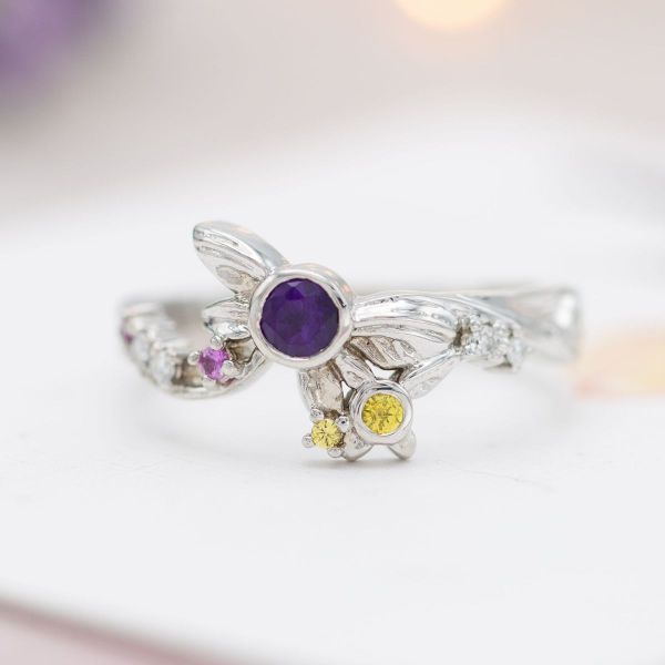 This ring pops with Legend of Zelda inspired fairy designs centered by a purple amethyst and yellow sapphire.
