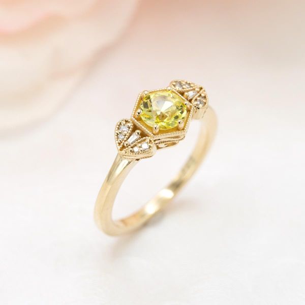 A vibrant yellow sapphire in a hexagonal gold setting with vintage inspired milgrain detailing.