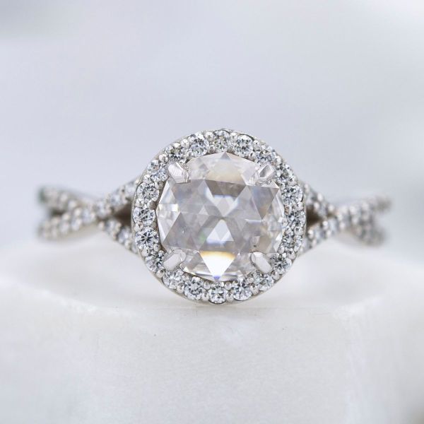 A halo of diamond accents surrounds the glassy rose cut center diamond in this engagement ring.