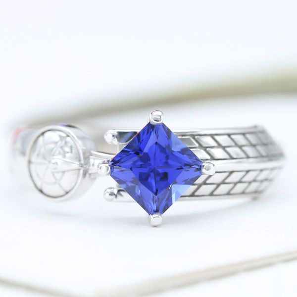 This engagement ring features a blue sapphire center stone and spaceships from Star Trek and Dr. Who