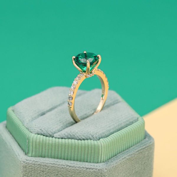 This engagement ring’s solitaire emerald is highlighted by diamond accents and a matching tiara wedding band.