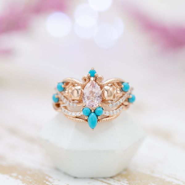 A pale pink morganite center stone with diamond and turquoise accents.