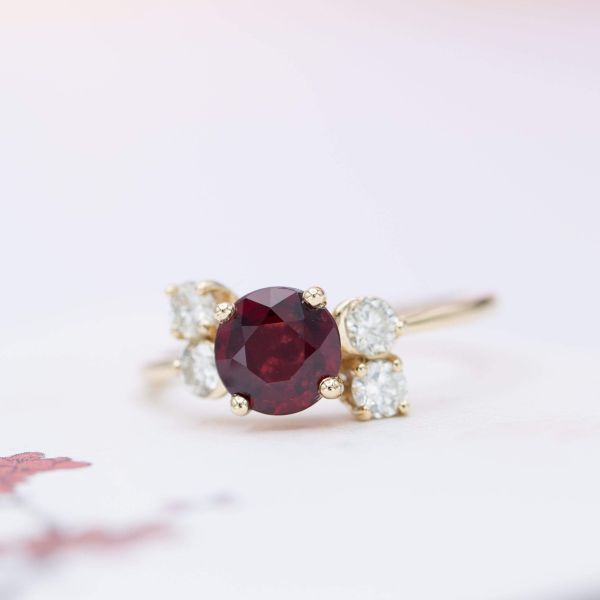 A delicate, asymmetrical cluster setting featuring a vivid red ruby center stone.