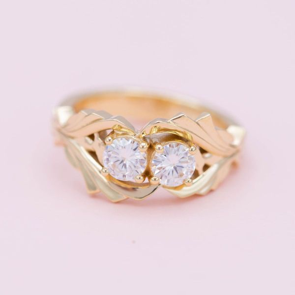 Two moissanites come together at the heart of this fantasy-inspired toi et moi engagement ring in yellow gold.