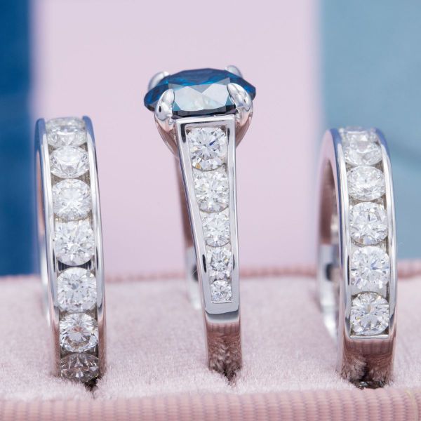 The clean lines of three channel-set diamond and white gold bands allow the blue diamond to take the spotlight in this bridal set.