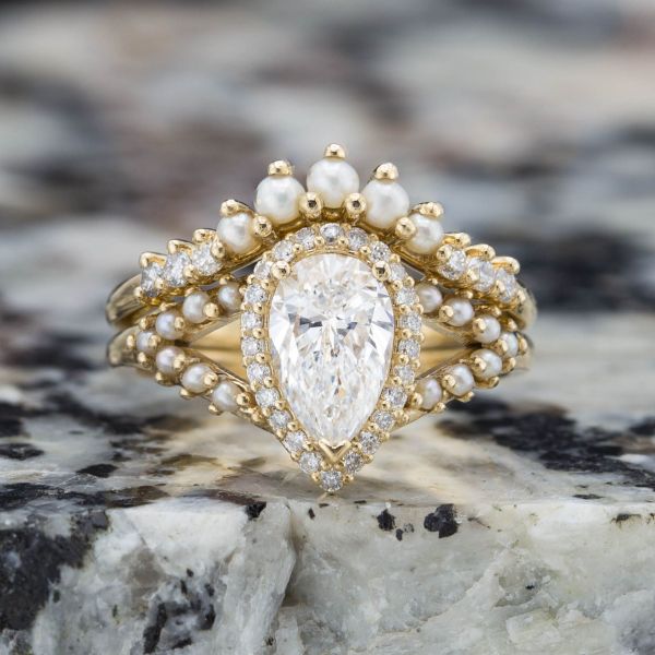 一套华丽的新娘套装将种子珍珠镶嵌在梨形切割钻石的中心。