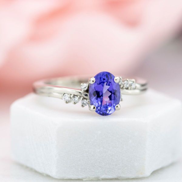 An oval tanzanite makes the central focus of this white gold engagement ring.