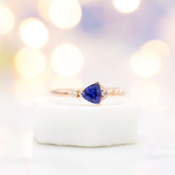 Asymmetrical tanzanite engagement ring, with trillion cut tanzanite facing across the band.