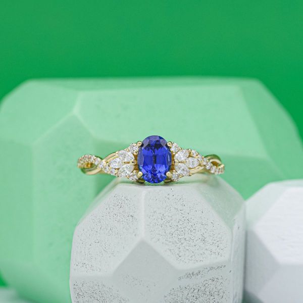 Lab created oval cut sapphire with diamond accents and yellow gold band.