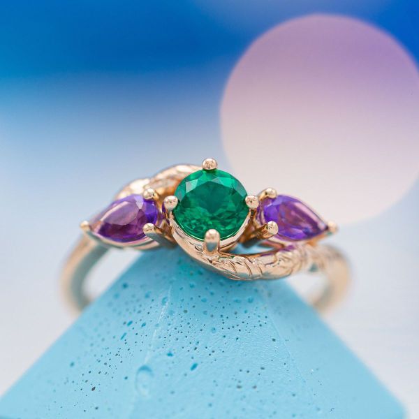 This nature and elf inspired engagement ring pops with bright green and violet gemstones on a band of chiseled vines.