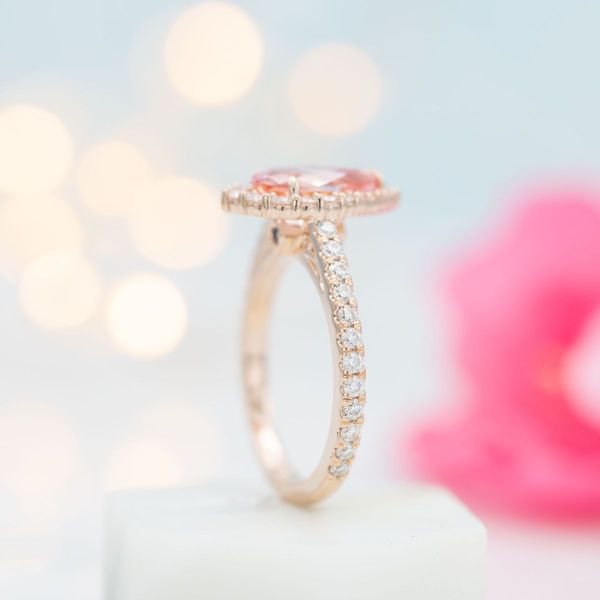 This engagement ring drips with sophistication as a halo of graduated moissanites frame the teardrop sapphire while more fall down the rose gold band.