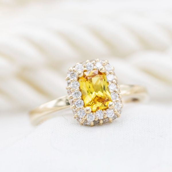 这枚订婚戒指星星明亮的黄色辐射切割蓝宝石在闪闪发光的钻石光环。